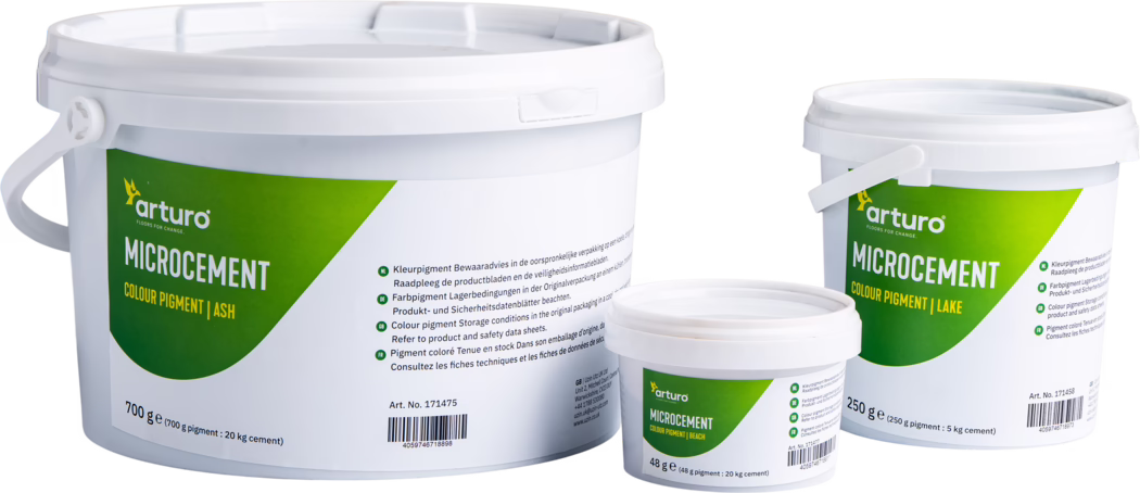 Arturo_Dummy_Microcement_Pigment_2022-11 Drie witte kunststofemmers van het merk Arturo met microcement-kleurpigmenten, gefotografeerd op een witte achtergrond. De drie verpakkingen (groot 700 g, middel 250 g, klein 48 g) hebben een groen-gele label met het 'arturo' logo en de tekst 'MICROCEMENT COLOUR PIGMENT' en tonen kleurnaam-varianten zoals Ash, Lake en Beach. Zichtbare details zijn afsluitbare deksels met handgrepen, gedrukte gebruiks- en bewaarvoorschriften in meerdere talen, een streepjescode en een artikelnummer; neutrale studiobelichting benadrukt de matte kunststofstructuur. Geschikt voor productvermeldingen, verpakkingsreferenties en webshops.