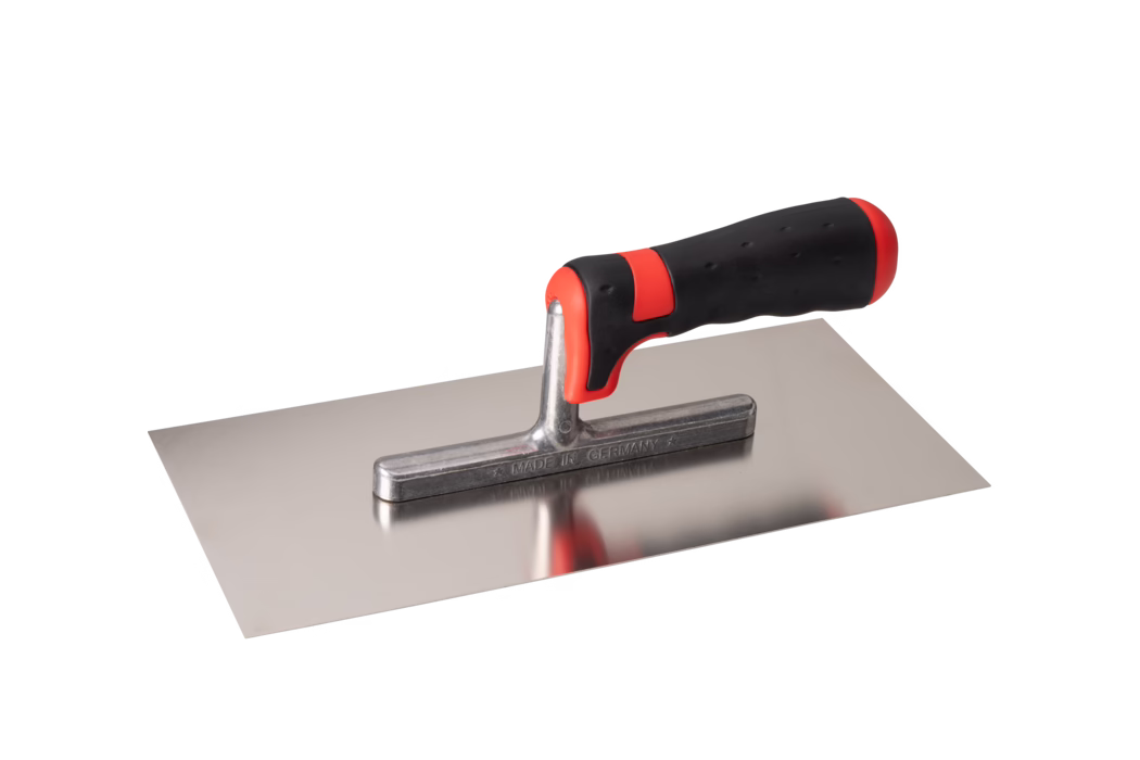 Rechthoekige roestvrijstalen pleisterspaan met een glad, vlak blad en een korte metalen hals waarop een ergonomisch gevormde zwart-rode softgrip-handgreep is gemonteerd. Het gepolijste blad is reflecterend en toont een lichte reflectie van de handgreep; de metalen hals is gemarkeerd met MADE IN GERMANY. De handgreep heeft rode accenten voor en achter en een gestructureerd rubberen oppervlak voor een veilige grip. Het gereedschap is vrijstaand gefotografeerd op een witte achtergrond vanuit een iets verhoogde zijkantshoek. Geschikt voor het aanbrengen en gladstrijken van mortel, pleister of voegmiddel.